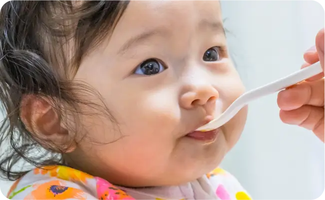 スプーンで離乳食を食べる赤ちゃん